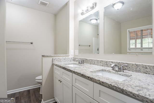 full bath with wood finished floors, a sink, toilet, and visible vents