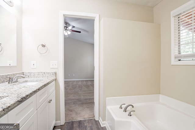 bathroom with vanity, baseboards, ceiling fan, and a bath