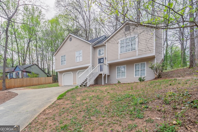 bi-level home featuring driveway, a garage, and fence