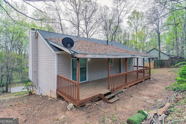 back of property with a deck, fence, and a chimney