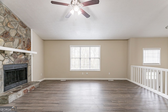 unfurnished living room featuring dark wood-style floors, a fireplace, baseboards, and a ceiling fan