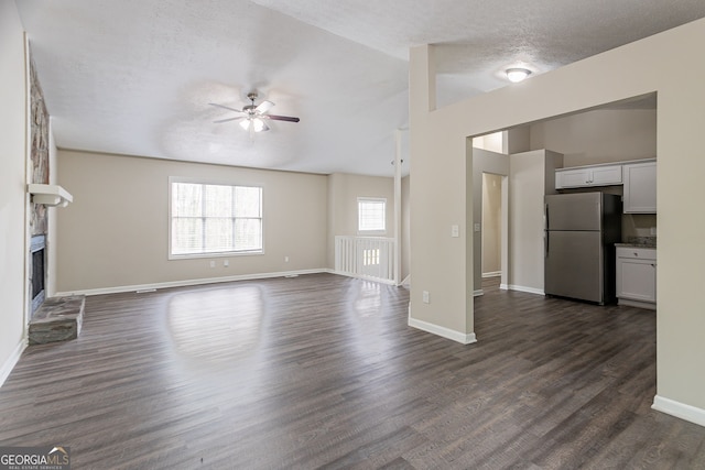 unfurnished living room featuring baseboards, a fireplace, ceiling fan, and dark wood-style flooring