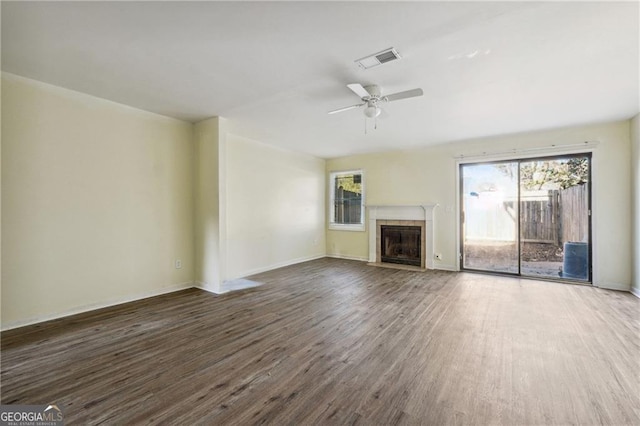unfurnished living room featuring visible vents, wood finished floors, a fireplace, and a healthy amount of sunlight