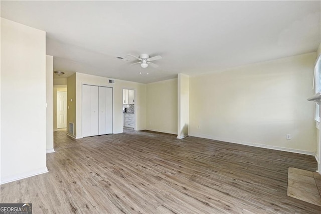 unfurnished living room with baseboards, visible vents, wood finished floors, and a ceiling fan