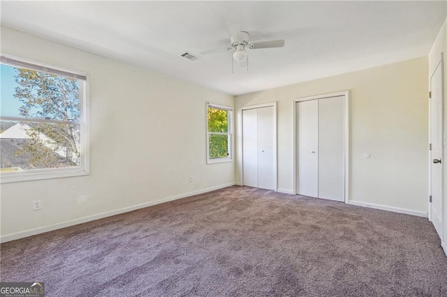unfurnished bedroom featuring baseboards, multiple closets, visible vents, and carpet