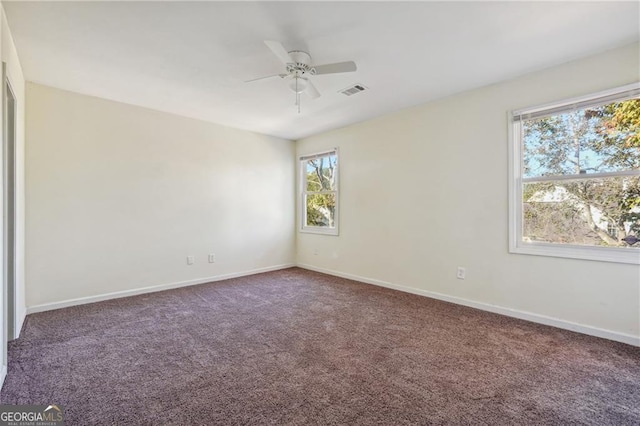 carpeted spare room featuring baseboards, ceiling fan, and visible vents