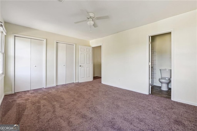 unfurnished bedroom featuring baseboards, carpet flooring, ensuite bath, and two closets