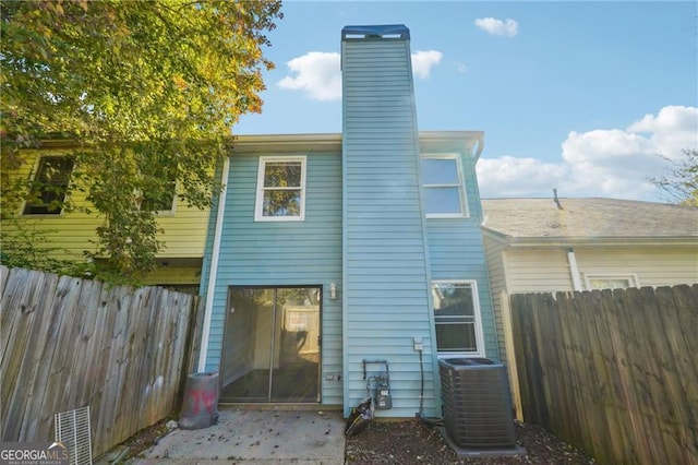 rear view of house featuring central AC unit, a chimney, fence, and a patio