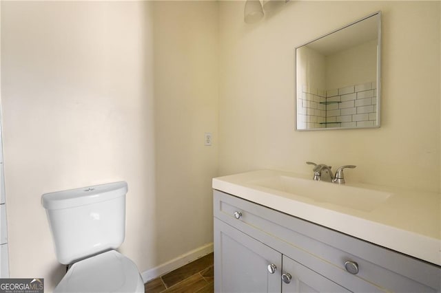 bathroom with toilet, vanity, baseboards, and wood finished floors