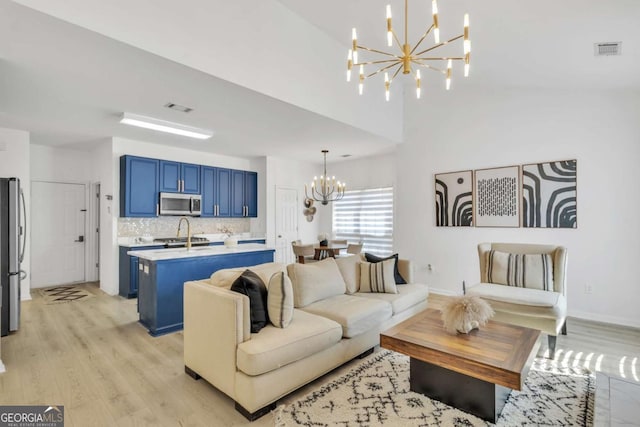 living area with baseboards, visible vents, light wood-style flooring, and a chandelier