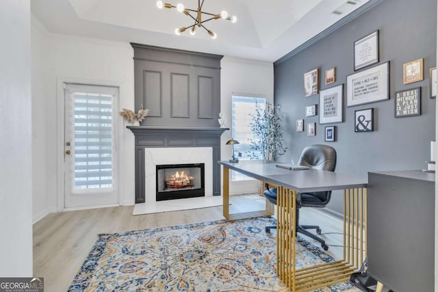 home office featuring a tray ceiling, a healthy amount of sunlight, wood finished floors, and a chandelier