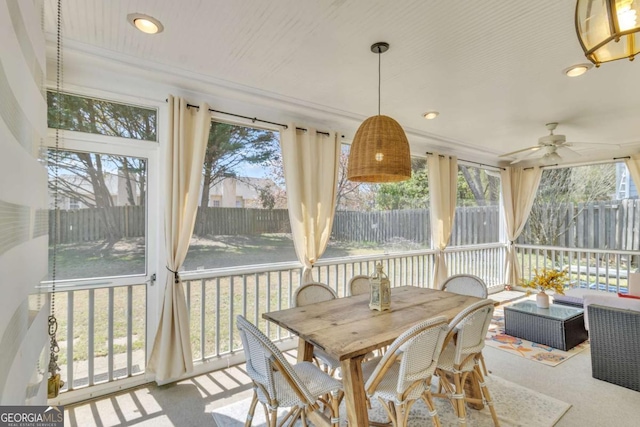 sunroom with outdoor dining area and a ceiling fan