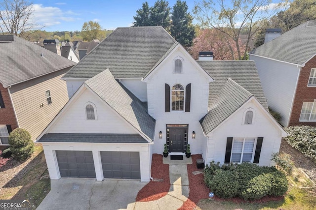 view of front of house with concrete driveway, a garage, roof with shingles, and a chimney