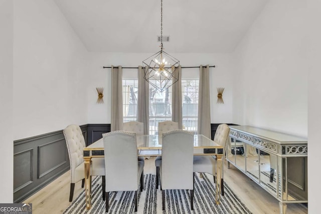 dining room featuring light wood-style flooring, visible vents, a chandelier, and wainscoting