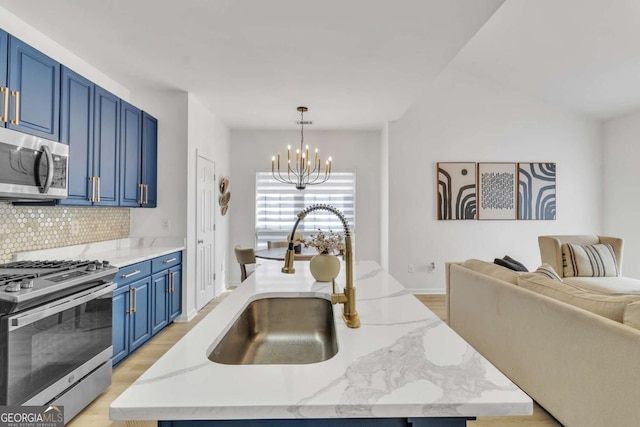 kitchen with a notable chandelier, a sink, open floor plan, stainless steel appliances, and blue cabinetry