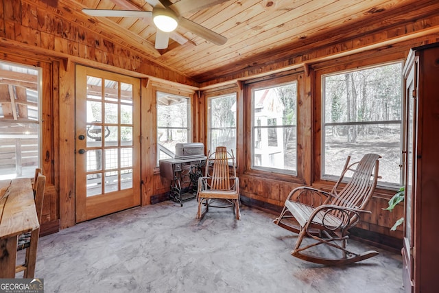 sunroom with unfinished concrete floors, wooden ceiling, and wood walls