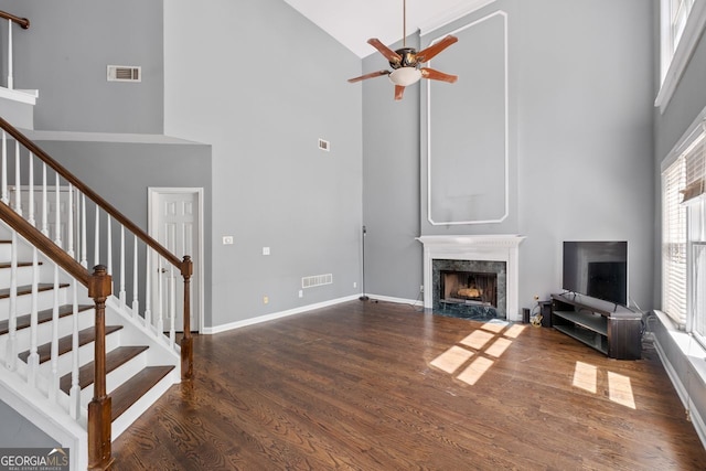 unfurnished living room featuring visible vents, a ceiling fan, wood finished floors, a fireplace, and high vaulted ceiling