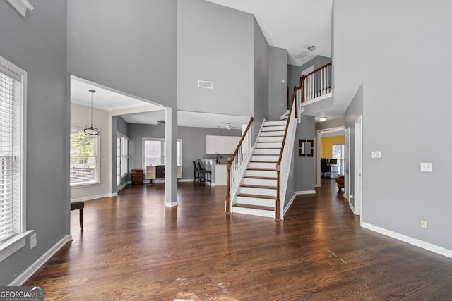 entryway with stairway, visible vents, a towering ceiling, and baseboards