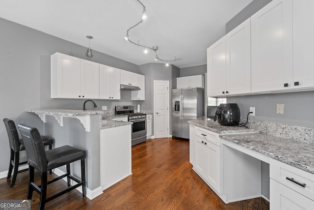 kitchen featuring a peninsula, under cabinet range hood, stainless steel appliances, and white cabinetry