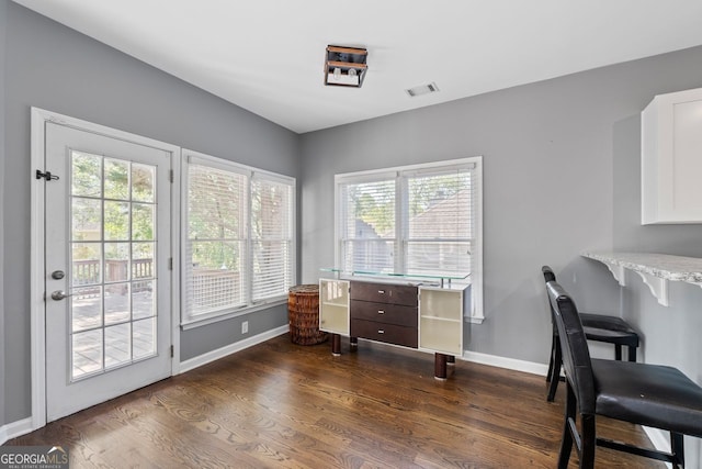 office space with baseboards, plenty of natural light, visible vents, and dark wood-style floors