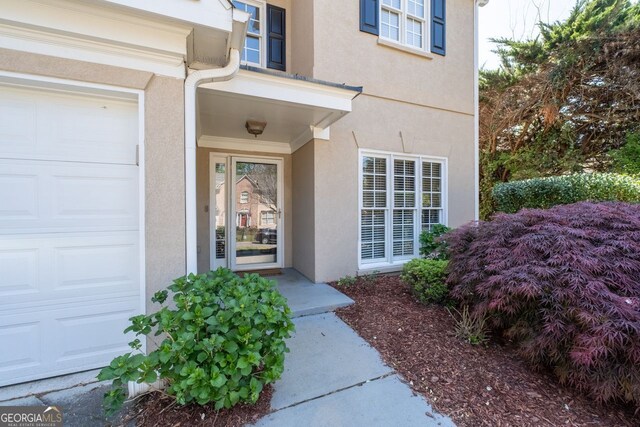 doorway to property with an attached garage and stucco siding