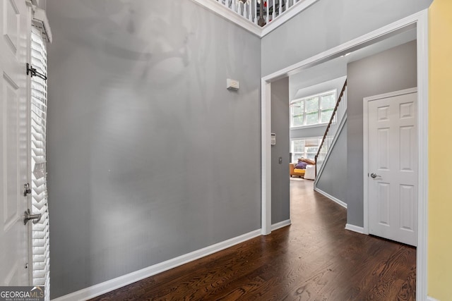 hallway with baseboards, dark wood-type flooring, and stairs