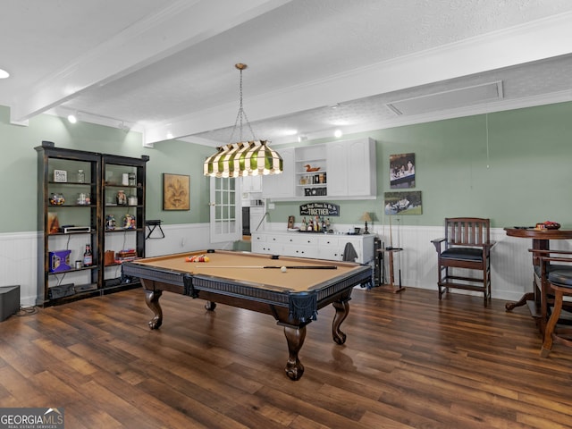 playroom with attic access, a wainscoted wall, beamed ceiling, crown molding, and wood finished floors