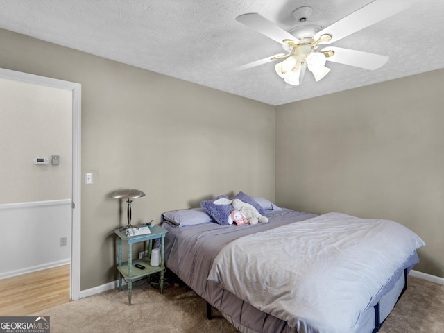 carpeted bedroom featuring a textured ceiling, baseboards, and ceiling fan