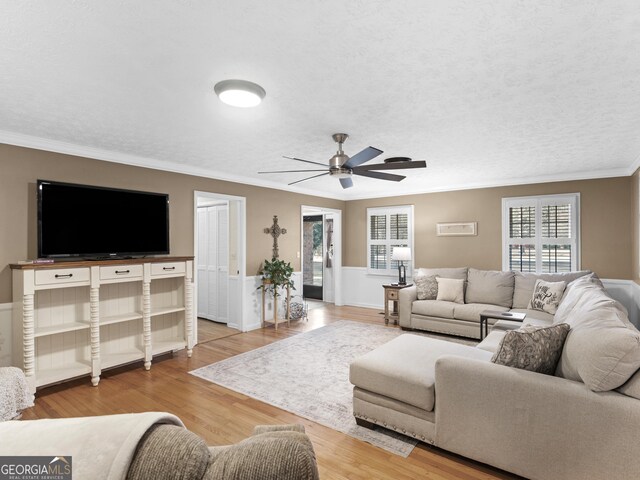 living room featuring ceiling fan, light wood-style floors, and crown molding
