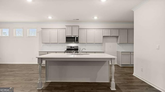 1099 Blue Juniper Cir, Loganville, GA 30052 - kitchen featuring crown molding, gray cabinetry, a center island with sink, a sink, and appliances with stainless steel finishes