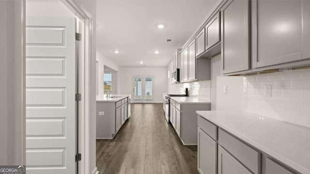 1099 Blue Juniper Cir, Loganville, GA 30052 - kitchen with appliances with stainless steel finishes, a sink, dark wood-style floors, gray cabinets, and backsplash