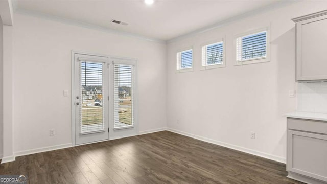 1099 Blue Juniper Cir, Loganville, GA 30052 - unfurnished dining area featuring dark wood finished floors, baseboards, visible vents, and ornamental molding