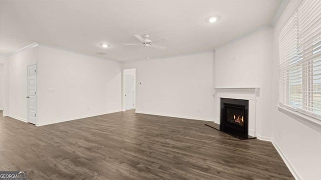 1099 Blue Juniper Cir, Loganville, GA 30052 - unfurnished living room with dark wood-style flooring, ornamental molding, baseboards, a lit fireplace, and ceiling fan