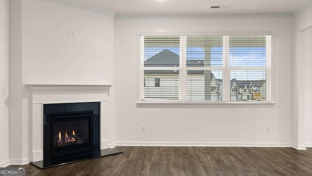 1099 Blue Juniper Cir, Loganville, GA 30052 - unfurnished living room featuring dark wood-style flooring, visible vents, crown molding, baseboards, and a glass covered fireplace