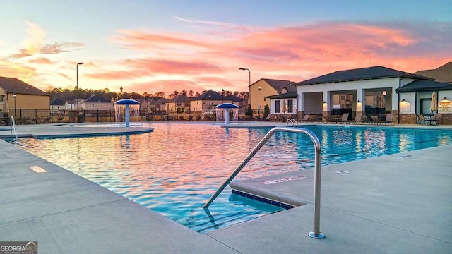 1099 Blue Juniper Cir, Loganville, GA 30052 - pool at dusk featuring a community pool, fence, and a patio