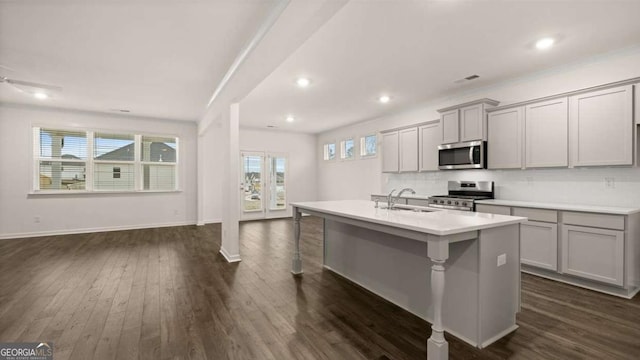 1099 Blue Juniper Cir, Loganville, GA 30052 - kitchen with gray cabinets, light countertops, appliances with stainless steel finishes, a center island with sink, and dark wood-style floors
