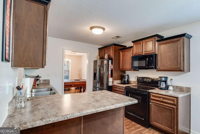 8166 N Pine Cone Dr, Villa Rica, GA 30180 - kitchen featuring visible vents, a peninsula, a sink, light wood-style floors, and black appliances