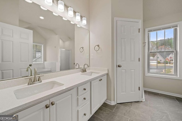 bathroom featuring baseboards, double vanity, and a sink