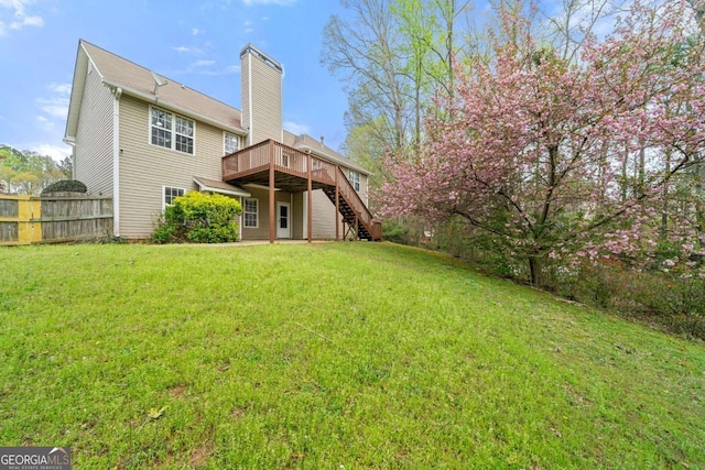 back of property featuring stairway, a chimney, fence, a deck, and a lawn