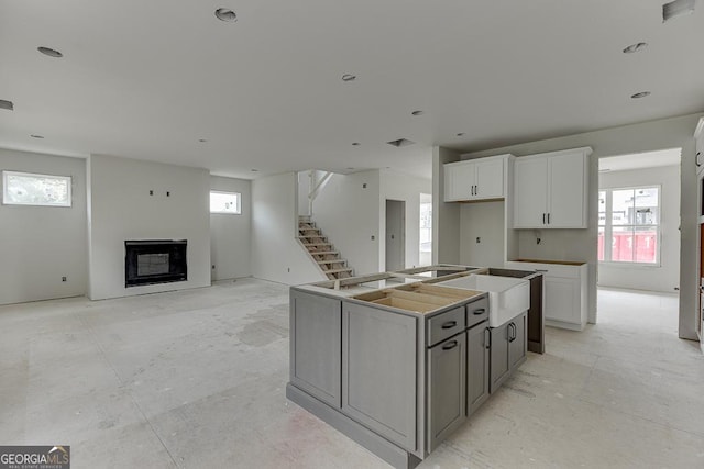 3748 Cheyenne Ln, Jefferson, GA 30549 - kitchen with a center island with sink, a glass covered fireplace, white cabinets, a sink, and wall oven
