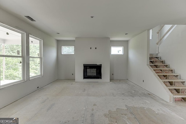 3748 Cheyenne Ln, Jefferson, GA 30549 - unfurnished living room with plenty of natural light, a glass covered fireplace, and stairway