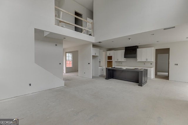 3787 Cheyenne Ln, Jefferson, GA 30549 - kitchen featuring white cabinets, a high ceiling, unfinished concrete flooring, a center island, and premium range hood