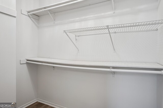 walk in closet with dark wood-style flooring
