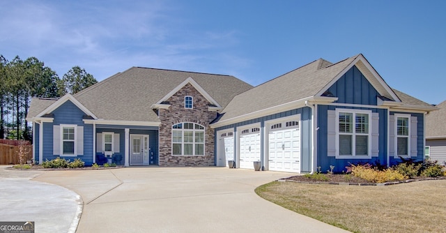 view of front facade featuring fence, roof with shingles, board and batten siding, concrete driveway, and an attached garage