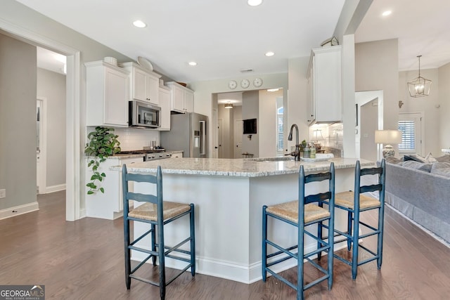kitchen with stainless steel appliances, tasteful backsplash, white cabinetry, and dark wood-type flooring