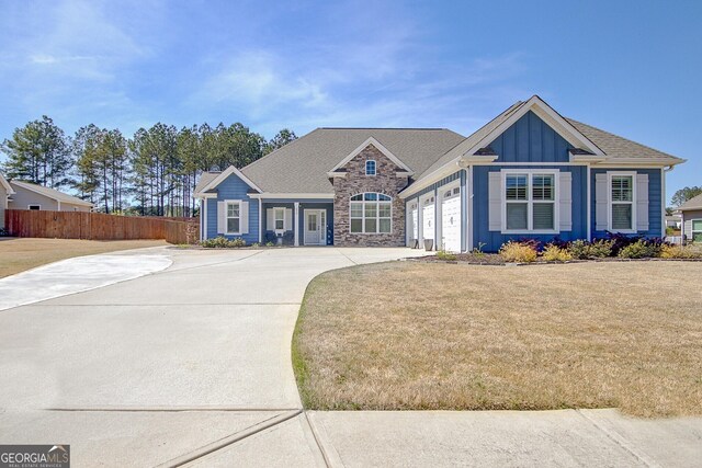 view of front of property featuring fence, a garage, board and batten siding, a front yard, and driveway