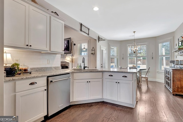 kitchen with wood finished floors, dishwasher, a sink, a peninsula, and white cabinetry