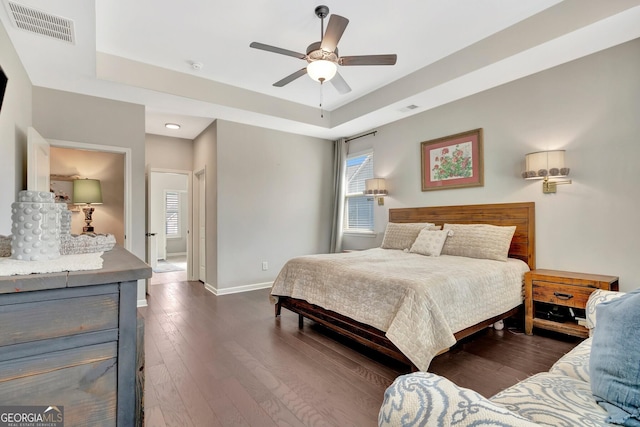 bedroom with baseboards, visible vents, multiple windows, and a raised ceiling