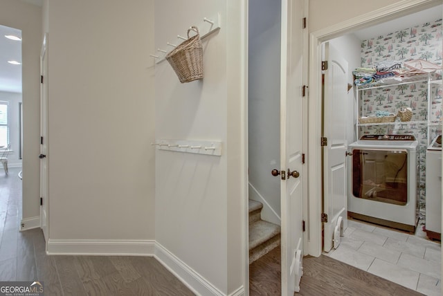 hallway featuring separate washer and dryer, baseboards, wood finished floors, and stairway