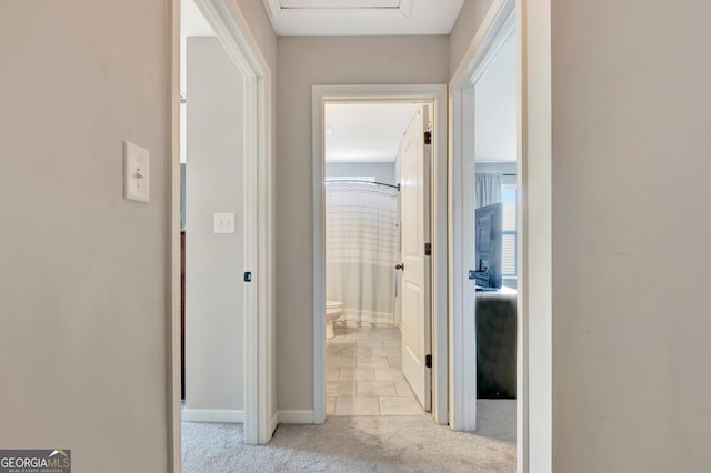 hallway featuring baseboards, carpet flooring, and tile patterned floors